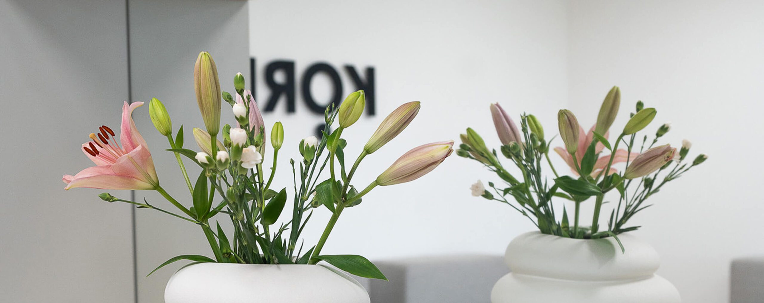 Moderner Empfang mit weißem Tresen und Blumen – stilvolle Praxisgestaltung für Veranstaltungen wie den Infoabend Fitness.