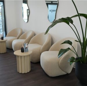 Moderner Empfangsbereich mit beigen Stühlen und Pflanze – einladender Ort an einem der Standorte der Physiotherapie.