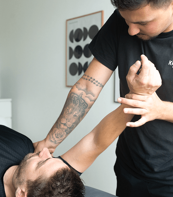 Tätowierter Physiotherapeut behandelt Schulter – individuelle Therapie zur Förderung von Gesundheit und Fitness Rodgau.