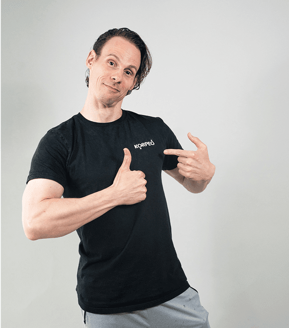 Mitarbeiter mit Korpeo-Shirt zeigt aufs Logo – Teamspirit bei deinem Physiotherapeuten in Lich.