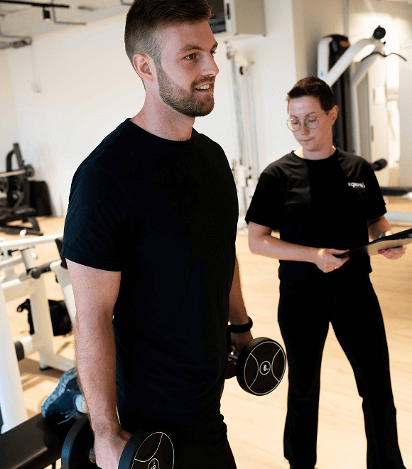 Trainerin begleitet Ausfallschritt-Übung mit Hanteln – professionelle Techniküberwachung bei Fitness Rodgau.