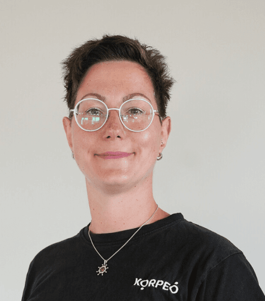 Lächelnde Mitarbeiterin im Korpeo-T-Shirt – freundliches Teammitglied im Trainings- & Fitnessbereich.