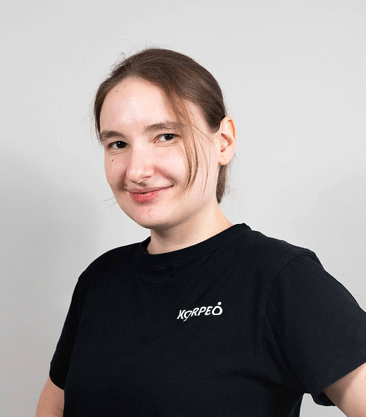 Lächelnde Mitarbeiterin im Korpeo-T-Shirt – freundliches Teammitglied in der Physiotherapie.