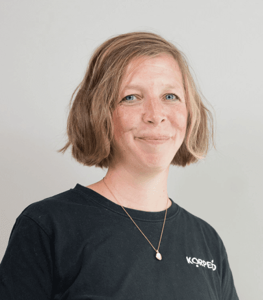 Lächelnde Mitarbeiterin im Korpeo-T-Shirt – freundliches Teammitglied in der Physiotherapie.