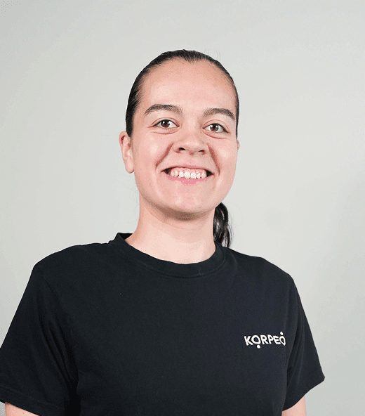 Lächelnde Mitarbeiterin im Korpeo-T-Shirt – freundliches Teammitglied in der Physiotherapie.