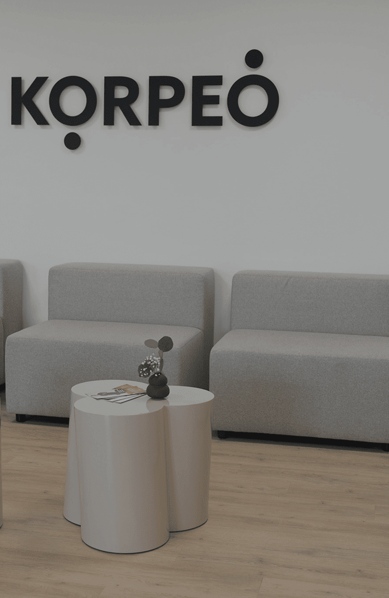 Empfangsbereich von Korpeo Rabenau mit moderner Holztheke und prominent platziertem Korpeo-Logo – einladender Eingangsbereich für Patienten und Besucher.