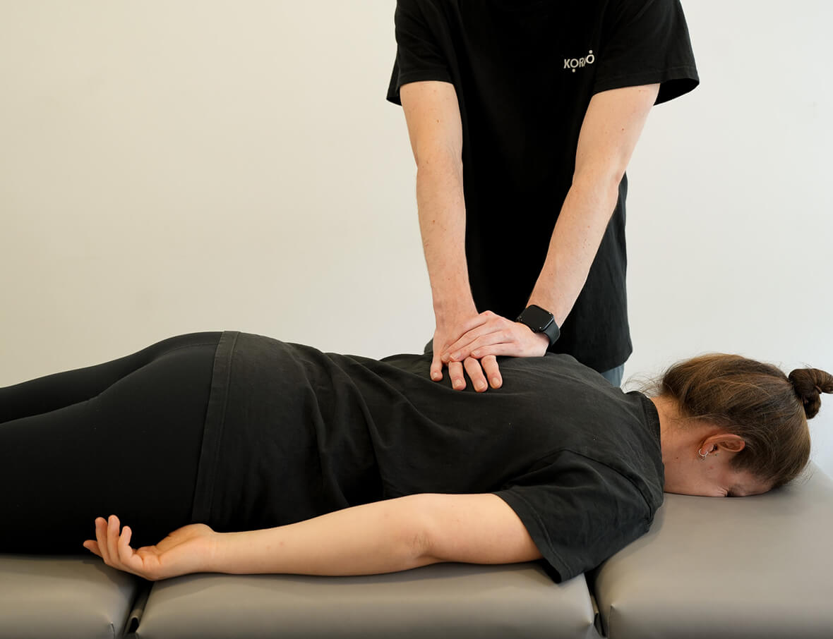 Frau erhält therapeutische Behandlung von männlichem Physiotherapeuten in ruhigem Behandlungsraum – professionelle Physiotherapie für Wohlbefinden und Genesung bei Korpeo.