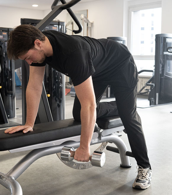 Physiotherapeut Benedikt führt eine Übung für den Rücken aus auf der Bank