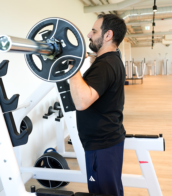 Physiotherapeut Vasilis fuehrt eine Hanteluebung durch auf der Trainingsflaeche