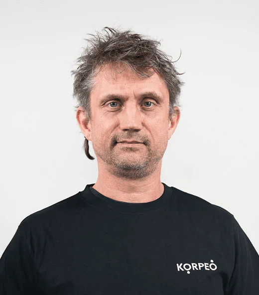 Lächelnder Mitarbeiter im Korpeo-T-Shirt – freundliches Teammitglied in der Physiotherapie.